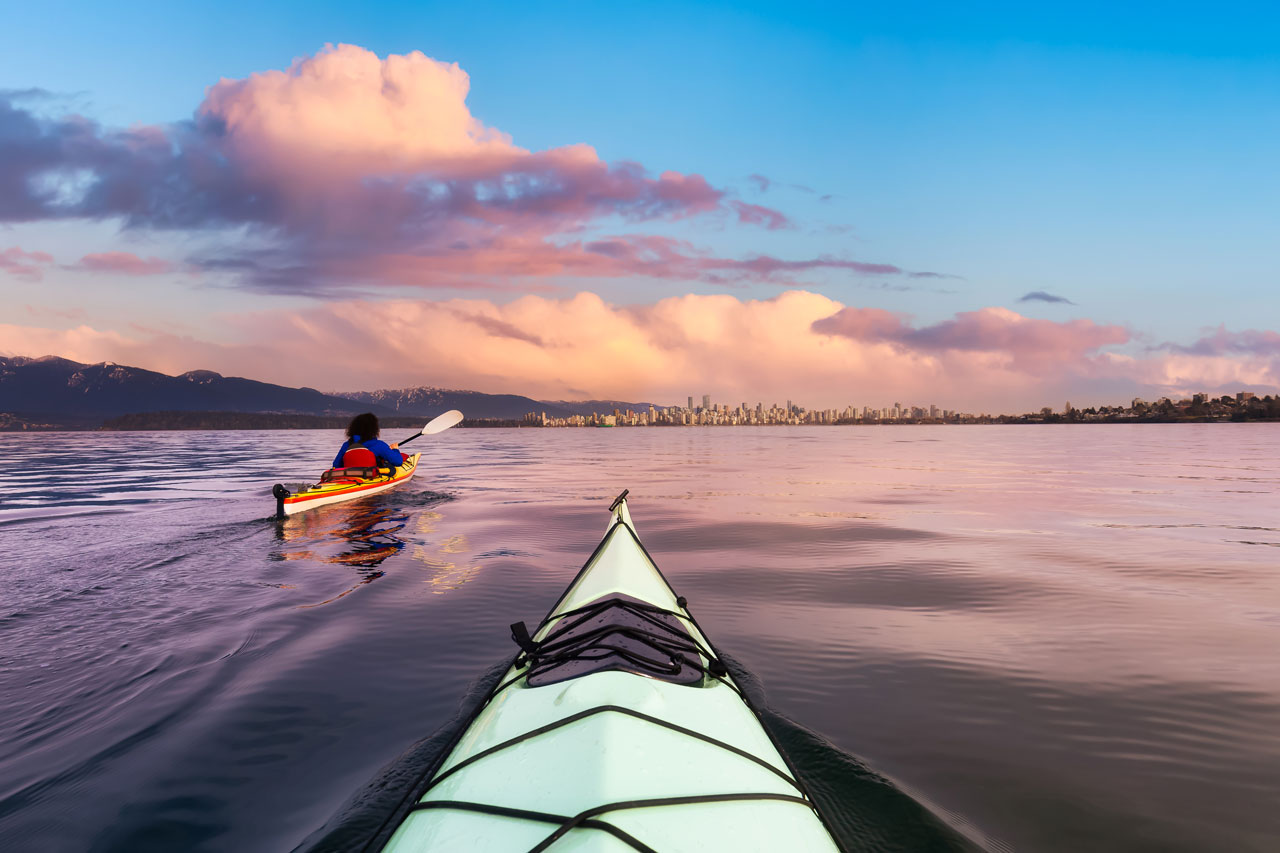 A kayaker paddling through Mission Bay in San Diego during a peaceful winter sunset, showcasing the beauty of kayaking Mission Bay in February.